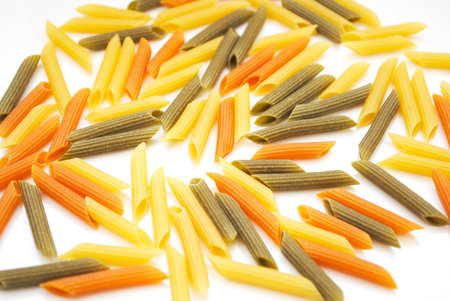 Closeup of Raw Cylinder-shaped Penne Pasta Noodles in Three Colors Yellow, Green and Red