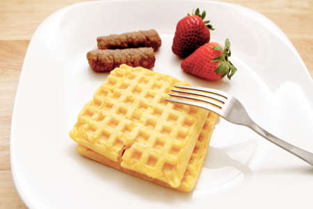 Fresh Strawberries, Waffles and Two Pork Sausage Links on a White Plateの写真素材