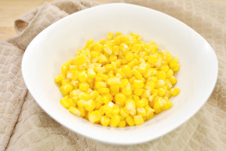 sweet corn in a white bowl on the tablecloth, top viewの写真素材