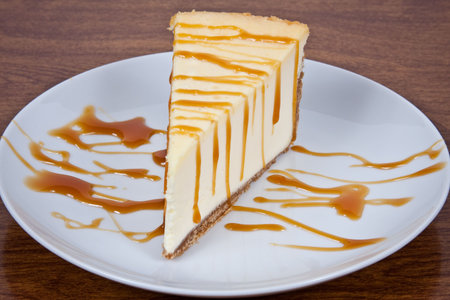 Cheesecake With Caramel Drizzled on Top Served on a White Plateの写真素材