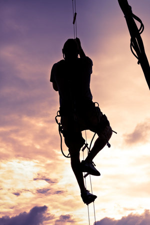 Silhouette Of A Man Climbing To The Topの写真素材