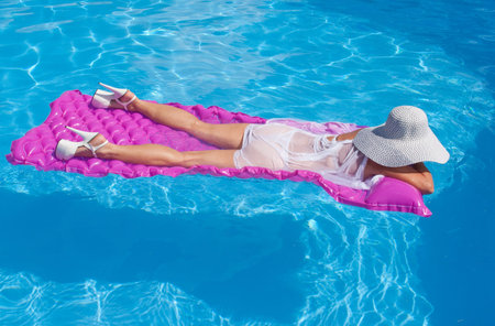 Woman wearing high heels floating on a pink float.の写真素材