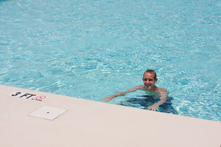 Young man having fun in the swimming pool in the summer