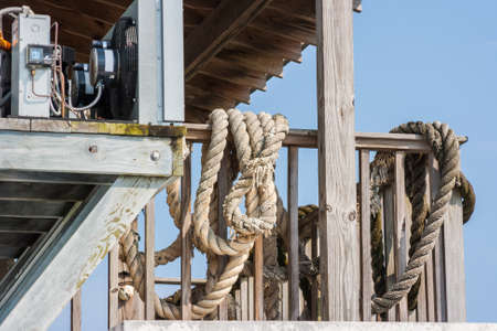 Large old ropes hanging on the deck railingの写真素材