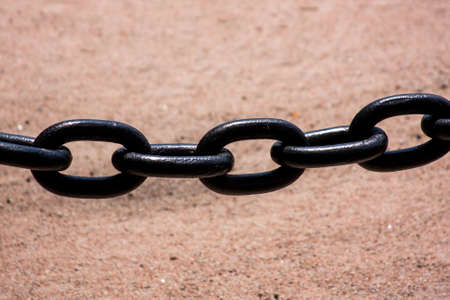 Large black metal chain with a stone color backgroundの写真素材