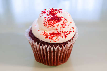 Red Velvet cupcake with white cream cheese frosting and sprinkled with red sugarの写真素材