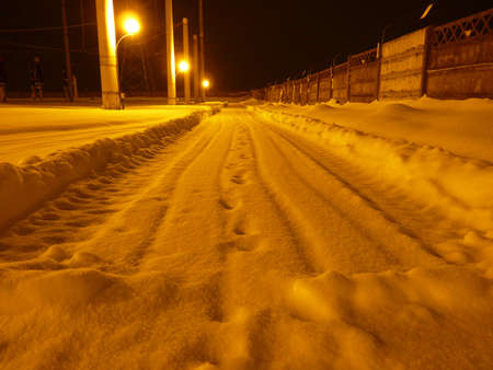 Road covered with snow and yellow warm lightingの写真素材