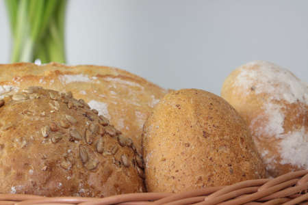 Basket of various fresh baked bread on wooden tableの写真素材