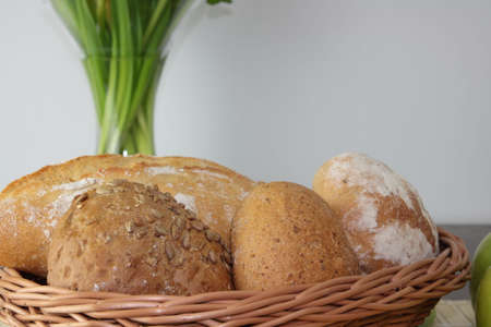 Basket of various fresh baked bread on wooden tableの写真素材