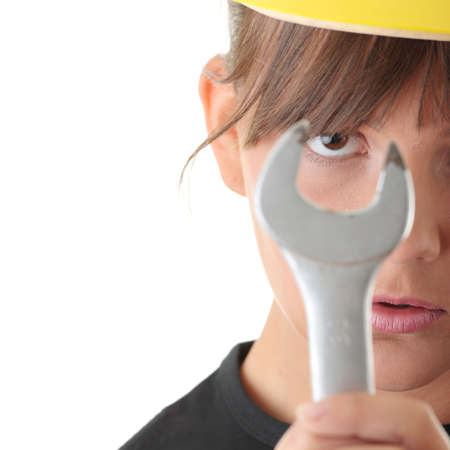 Young woman builder at work with big french key, isolated on white - focus on eyeの写真素材