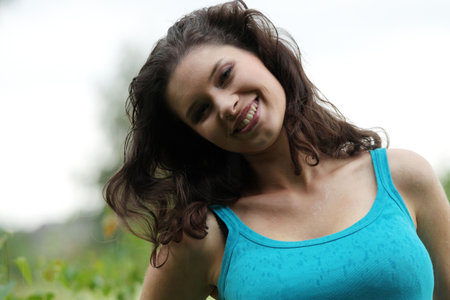 Beautiful young woman relaxing in the grass (rain in summer)の写真素材