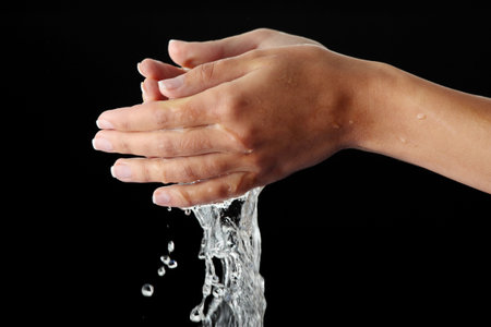 Beautiful female hands with water isolated on black background
