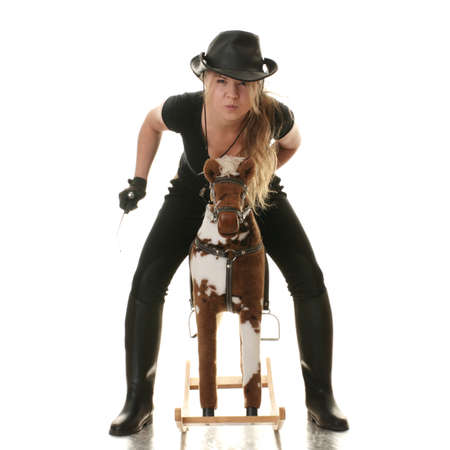 Young beautiful cowgirl (jockey) race on hobbyhorse with face expression isolated on white background (race concept).の写真素材