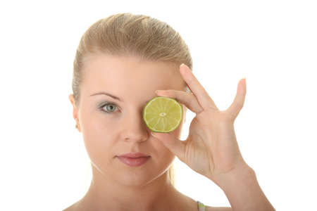 Young woman holding a slice of lime in front of her eye isolated on white backgroundの写真素材