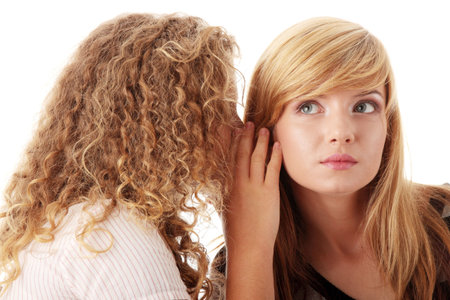 Two happy young girlfriends talking isolated over whiteの写真素材