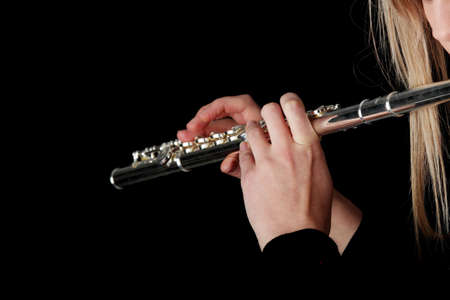 Portrait of a woman playing transverse flute, isolated on blackの写真素材