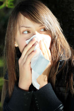 Teen Girl blowing her nose outdoors in late autumn.の写真素材