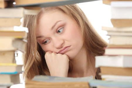 Young woman sitting behind books - tiredの写真素材