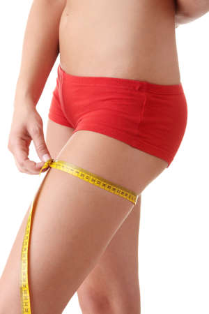 Young caucasian woman in red lingerie measuring her body, isolated on whiteの写真素材