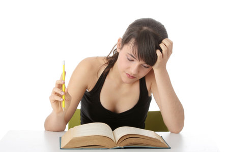 Teen girl learning at the desk , isolated on white
