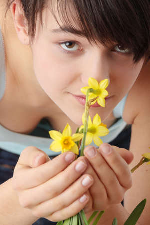 Teen girl smelling yellow spring flowers の写真素材