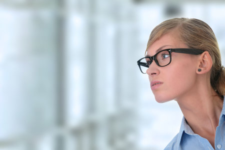 Portrait of a thoughtful young woman in blue shirt and glasses (student, secretary or businesswoman)