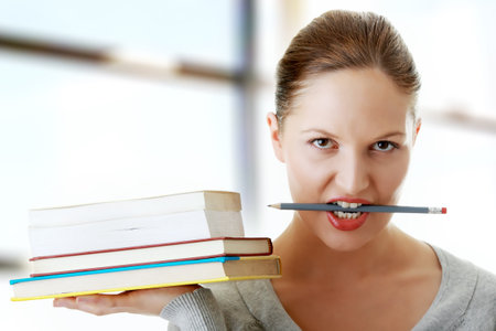Young caucasian student with books on hand and pencil in mouth