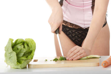 Sexy woman preparing healthy food salad with green vegetable and knifeの写真素材