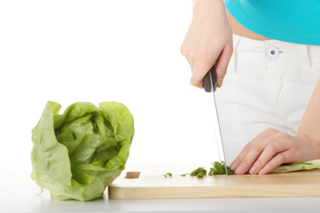 Woman preparing healthy food salad with green vegetable and knifeの写真素材