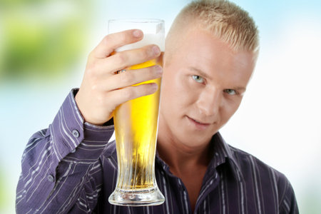 Happy young man holding a glass of beerの写真素材