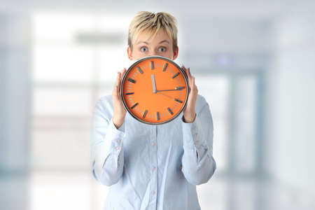 Woman holding big alarm clock, isolated on white backgroundの写真素材