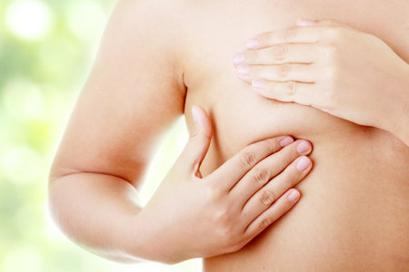 Young Caucasian adult woman examining her breast for lumps or signs of breast cancerの写真素材