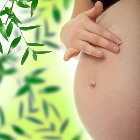 Young pregnant woman rubs cream into her belly の写真素材