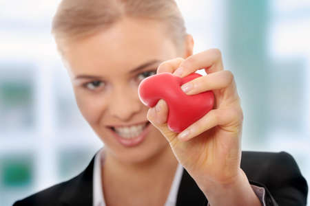 Young business woman holding heart shaped toy の写真素材