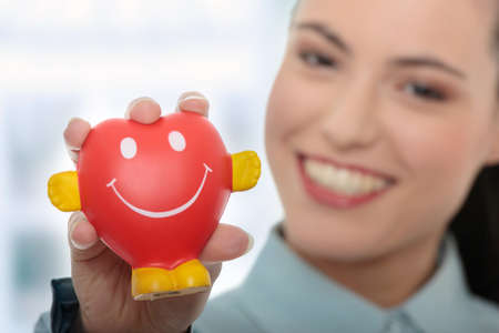 Young business woman holding heart shaped toyの写真素材