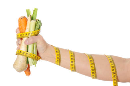 Woman's hand holding vegetables and measuring tape, isolated on white. Diet conceptの写真素材