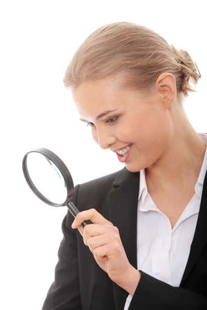 Young attractive smiling business woman looking into a magnifying glass, isolated on white background の写真素材