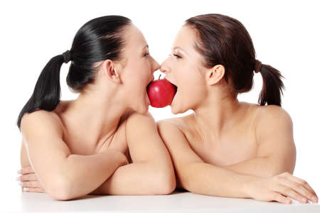 Two young woman biting an apple, isolated on white の写真素材