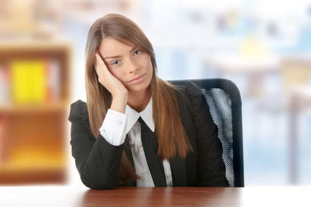 Stressed young woman sitting behind a deskの写真素材
