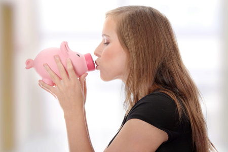 Young teen woman kissing a piggy bankの写真素材