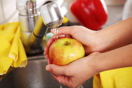 Woman hands washing tasty appleの写真素材