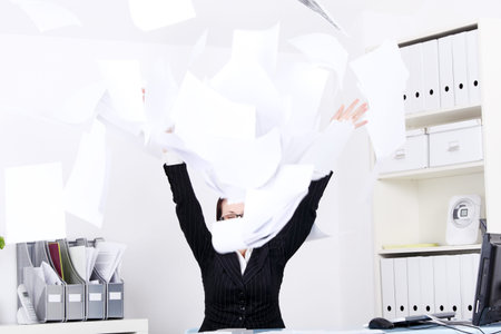 Caucasian businesswoman throwing sheets of paper in the office.
