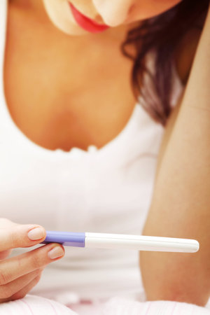 closeup of a worried woman looking at a pregnancy test, zoom in on the test.