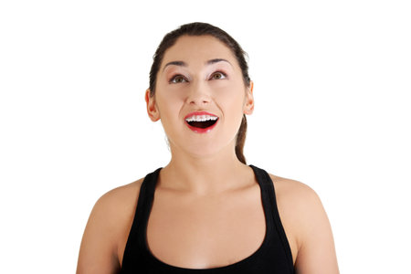 Portrait of a happy amazed young woman looking up. Isolated on white