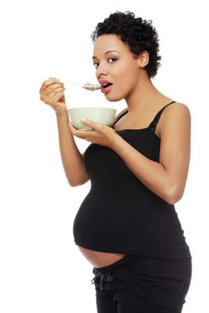 Site view portrait of a beautifyl young woman holding a spoon with cereal next to her lips, isolated on a white background.の写真素材