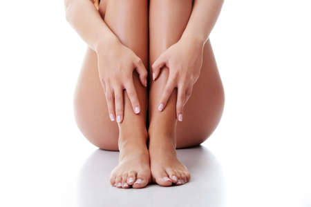 Woman holding on leg. Isolated on whiteの写真素材