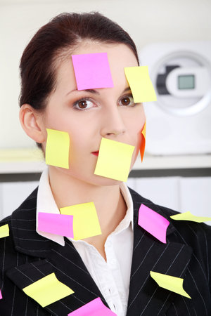 Beautiful caucasian businesswoman sitting in the office with post it notes on her body. 