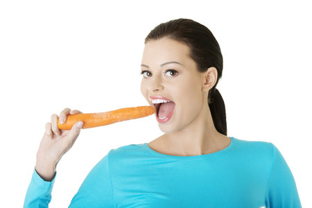 Fit young happy beautiful woman with carrot, isolated on whiteの写真素材