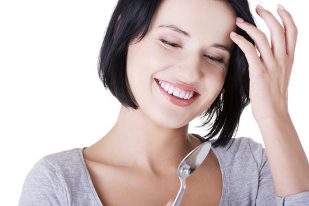 Young smiling woman with spoon (pleasure from eating), isolated on whiteの写真素材