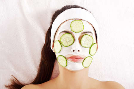 Young woman with cucumber slices on the face in a spa saloon の写真素材